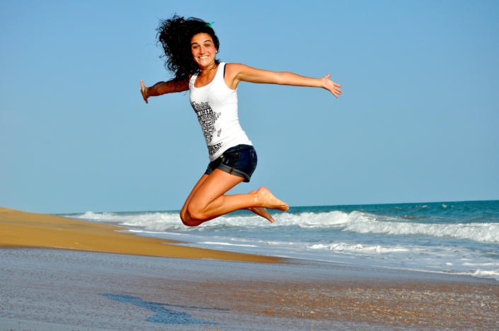 woman jumping on beach benefits of red light therapy